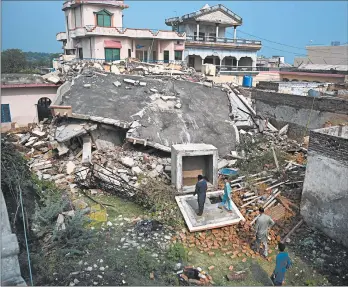  ?? AAMIR QURESHI/GETTY-AFP ?? Residents of the Mirpur district in Pakistan-controlled Kasmir examine a collapsed house Wednesday, the day after a 5.8 magnitude earthquake struck the area. Officials said the death toll was at least 37 as they began distributi­ng tents, food and water.