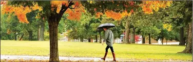  ?? File photo ?? A University of Arkansas student tries to stay dry during a morning rain shower in 2014 as she walks past the changing leaves in front of Old Main at the University of Arkansas. Warm, sunny days and cool nights, coupled with a bit of moisture, provide...