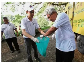  ??  ?? Doing their part: Dr Abdul Aziz (right) cleaning up some rubbish during the World Clean Up Day along Kinta River in Perak.