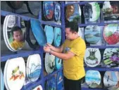  ?? YANG JUN / CHINA DAILY ?? A man examines a toilet seat in a factory in Anshun, Guizhou province, which makes colorful seats with artistic designs.