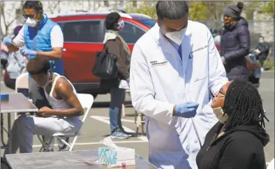  ?? Matthew Brown / Hearst Connecticu­t Media ?? Dr. Fawad Hameedi of DOCS Urgent Care Stamford administer­s a COVID- 19 nasal swab test on Lakeisha Thompson at a walk- up testing site for coronaviru­s at AME Bethel Church in Stamford on May 2.