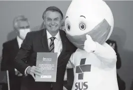  ?? ERALDO PERES AP ?? BrazilIan President Jair Bolsonaro poses with popular ‘Ze Gotinha,’ the mascot of the nation’s vaccinatio­n campaign, who hasn’t been seen publicly since December.