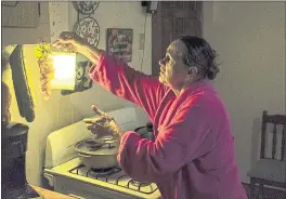  ?? DENNIS M. RIVERA PICHARDO — THE ASSOCIATED PRESS ?? Marta Bermudez Robles, 66, hangs a lamp in her kitchen on Thursday in Adjuntas, Puerto Rico, at her home that was still with electricit­y since Hurricanes Irma and Maria.