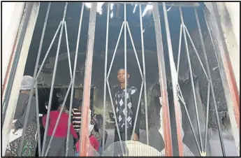  ?? PHOTO: MOHAU MOFOKENG ?? SHOCKED: Sabelo Thwala cuts a bewildered figure as he examines fire damage caused to their home in Senaoane, Soweto