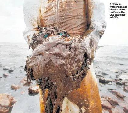  ?? ?? A clean-up worker handles blobs of oil and residue in the Gulf of Mexico in 2010.