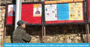 ?? — AFP ?? TRONGSA, Bhutan: In this picture taken on December 31, 2023, a man reads an election board ahead of the upcoming parliament­ary elections in Trongsa.