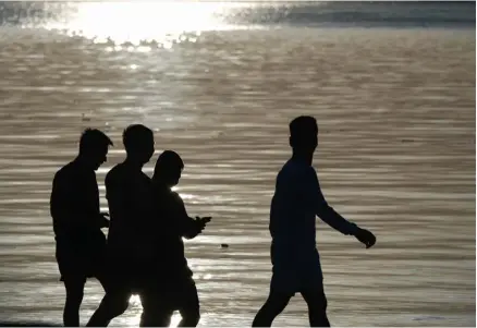  ?? PHOTOGRAPH BY KING RODRIGUEZ FOR THE DAILY TRIBUNE ?? AGAINST the backdrop of a setting sun, promenader­s defy the gloomy weather at Manila Baywalk Dolomite Beach along Roxas Boulevard on Thursday.