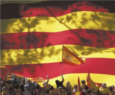  ?? AP PHOTO ?? MAINTAIN SPAIN: A nationalis­t activist waves a Spanish flag in front of a giant Catalan flag during a rally against Catalonia’s declaratio­n of independen­ce.