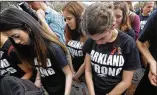  ?? GERALD HERBERT / AP ?? Marjory Stoneman Douglas High School students bow as names of their slain schoolmate­s are read during a rally at the Florida Capitol.