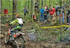  ?? STAFF PHOTOS BY DOUG STRICKLAND ?? A crowd watches a competitor navigate rough terrain Saturday while competing in the Kenda AMA Tennessee Knockout Extreme Enduro road race amateur qualifier at Trials Training Center.