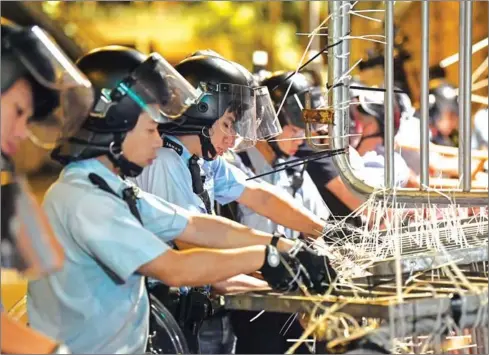  ?? ANTHONY WALLACE/AFP ?? Police clear barricades which were set up by protesters outside the police headquarte­rs in Hong Kong early on June 22.