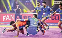  ?? ?? U Mumba raider Ajith Kumar (in orange and black) tries to escape the Tamil Thalaivas defence