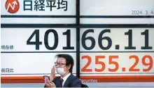  ?? Reuters-Yonhap ?? A man uses a smartphone in front of an electronic screen displaying Japan’s Nikkei share average outside a brokerage in Tokyo, Monday.