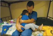  ?? JULIO CORTEZ — THE ASSOCIATED PRESS ?? Elmer Maldonado, a migrant from Honduras, hugs his 1-year-old son at a shelter in Harlingen, Texas, on Monday.