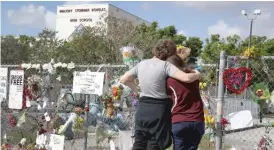  ?? | GETTY IMAGES ?? Joellen Berman and Margarita Lasalle look at amemorial in front of Marjory Stoneman Douglas High School in Parkland, Fla., where 17 people were killed on Feb. 14.