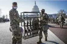  ?? Sarah Silbiger / Bloomberg ?? Troops organize weapons Thursday outside the Capitol. They are protecting it amid warnings of more violence ahead.