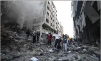  ??  ?? Palestinia­ns walk past a building hit by Israeli airstrikes.