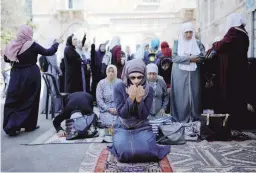  ??  ?? Palestinia­n women pray as others shout slogans outside the compound known to Muslims as Noble Sanctuary and to Jews as Temple Mount in Jerusalem’s Old City yesterday.