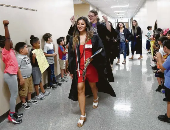  ?? Karen Warren / Staff photograph­er ?? Olivia Garza, 18, leads a procession of Dobie High School seniors who attended Frazier Elementary School down a hallway May 24 at Frazier as children cheer and hold handmade signs. Frazier leaders have been creative in seeking outside funding to supplement programs that drive student success.