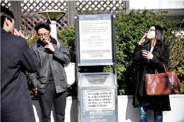  ??  ?? Photo shows people smoking cigarettes at a designated outdoor smoking area in the Naka-Meguro,Tokyo. — AFP photo