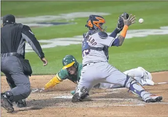  ?? TONY AVELAR — THE ASSOCIATED PRESS ?? The A’s Ramon Laureano scores as Astros catcher Martin Maldonado (15) waits for the throw on a sacrifice fly hit by Mitch Moreland during the fourth inning on Friday in Oakland.