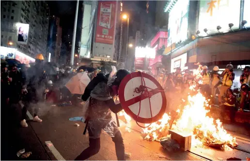  ?? AP ?? A protester uses a shield to cover himself as he faces policemen in Hong Kong.