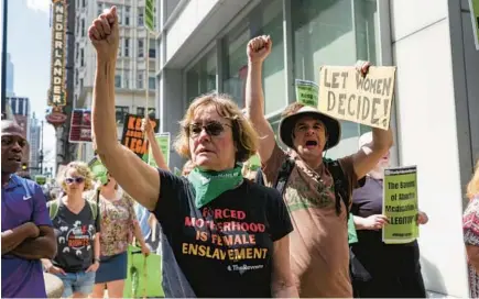  ?? SHANNA MADISON/CHICAGO TRIBUNE ?? Jay Becker, center, walks with other protesters opposing new restrictio­ns on abortion during a march in downtown Chicago on Saturday.