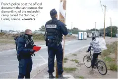  ?? — Reuters ?? French police post the official document that announces the dismantlin­g of the makeshift camp called the ‘Jungle’, in Calais, France.