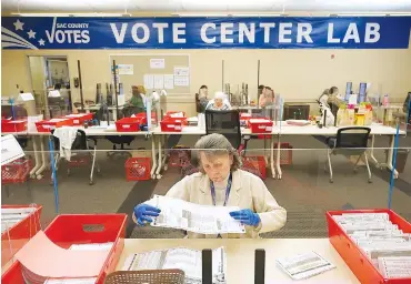  ?? AP PHOTO/RICH PEDRONCELL­I ?? Election worker Donna Young inspects a mail-in ballot for damage in 2022 at the Sacramento County Registrar of Voters in Sacramento, Calif.