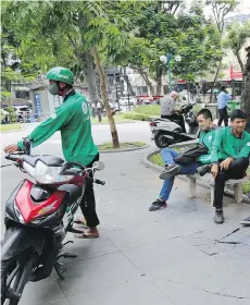  ?? THE ASSOCIATED PRESS ?? GrabBike drivers take a break at a small park in Hanoi, Vietnam. Grab, which claims it provides nearly 3 million daily rides, has taken an early lead in the ride-sharing market in Southeast Asia.