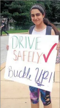  ??  ?? Teen Advisor for CAST, Lyann Abubaker, holds a sign to remind students to wear seat belts.