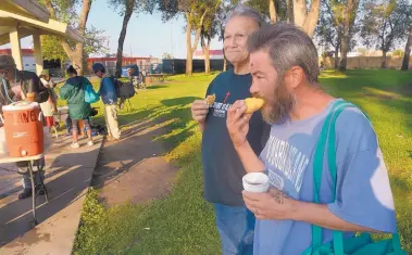  ?? GREG SORBER/JOURNAL ?? Charles Saiz, right, has coffee and bagel in Coronado Park on Sunday. With him is David Sanchez, who brought the food and helped serve the hundreds of homeless people who gather there every Saturday and Sunday morning for a prayer service and a meal.