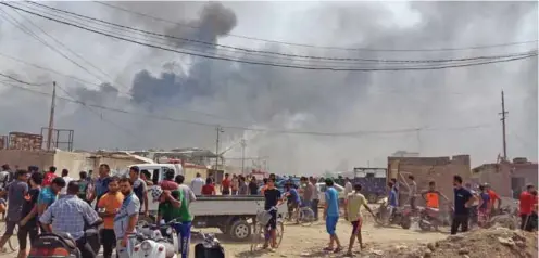  ?? – AFP ?? MASSIVE EXPLOSION: Smoke billows from buildings in a northeaste­rn neighbourh­ood of the Iraqi capital Baghdad where several blasts, including at a weapons storage facility, rocked the area on Friday, security sources said.