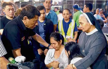  ??  ?? Sharing the grief: Duterte (left) comforting a relative of one of the victims after a fire engulfed a shopping mall in