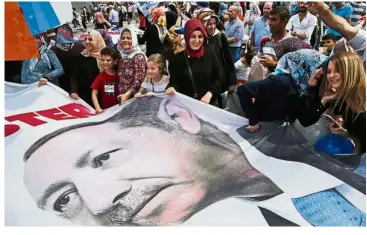  ?? — AP ?? Loyal support: People waving a banner with a picture of Erdogan during a gathering of the ruling Justice and Developmen­t Party (AKP) supporters in Istanbul.