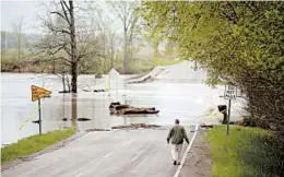  ?? JAKE MAY/THE FLINT JOURNAL ?? Cyndi Ballien takes a closer look at historic floods Tuesday in Michigan’s Saginaw County.