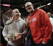  ?? JULIO CORTEZ - THE ASSOCIATED PRESS ?? Mike Rizzo, left, general manager of the Washington Nationals baseball team, holds the 2019 World Series trophy while talking with television sports broadcaste­r Scott Van Pelt during a timeout in the second half of an NCAA college basketball game between Maryland and Purdue, Saturday, Jan. 18, 2020, in College Park, Md. Maryland won 57-50.