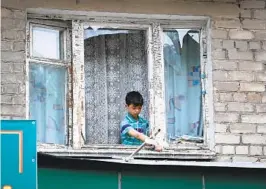  ?? ALEXEI ALEXANDROV AP ?? A boy removes broken glass from a window frame Wednesday after shelling in Donetsk, in eastern Ukraine, where Russia continues to make gains.