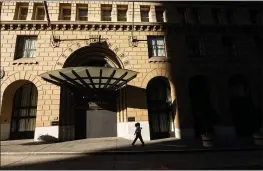  ?? NOAH BERGER — THE ASSOCIATED PRESS FILE ?? A pedestrian passes a boarded-up entrance to the Omni San Francisco Hotel, which has suspended operations due to the COVID-19 pandemic.