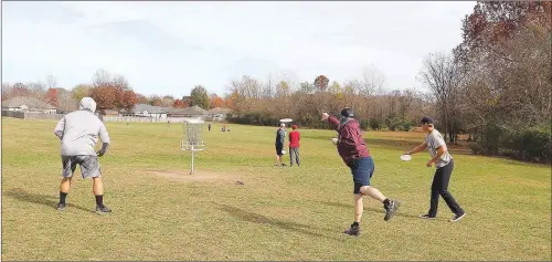  ??  ?? Players competing in a disc golf tournament at Creekside Park warm up on the course’s practice basket.