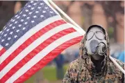  ?? PAUL SANCYA/ASSOCIATED PRESS ?? A protester wears a gas mask during a rally in response to Michigan’s coronaviru­s stay-at-home order at the State Capitol in Lansing, Mich. Thursday.