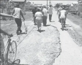  ??  ?? Residents of Victoria, East Coast Demerara, walking along Middle Walk Road where two large potholes and structural faults can be seen on both sides (Dhanash Ramroop photo)