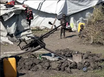  ??  ?? An anti-aircraft gun sits among families’ tents in flood-hit Pibor. Children played everywhere, despite the thick, glutinous mud and overflowin­g latrines.