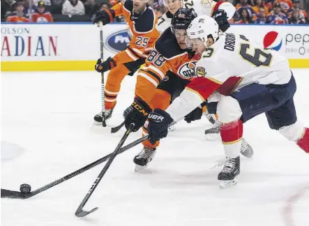  ?? JASON FRANSON/THE CANADIAN PRESS ?? Panthers winger Evgenii Dadonov tries to outhustle Oilers defenceman Brandon Davidson for a loose puck Monday night at Rogers Place. Dadonov had two goals in Florida’s 7-5 victory.