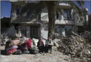  ?? VAHID SALEMI — THE ASSOCIATED PRESS ?? Survivors sit in front of a destroyed house on the earthquake site in Sarpol-e-Zahab in western Iran, Tuesday. Rescuers are digging through the debris of buildings felled by the Sunday earthquake in the border region of Iran and Iraq.