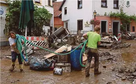  ?? AFP PIC ?? Residents cleaning a street damaged by floods in Bad Neuenahr-Ahrweiler, western Germany, on Friday.