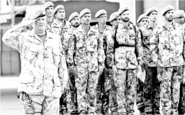  ?? — AFP photo ?? A Canadian soldier of the MINUSMA salutes as Germans soldiers stand guard at the contigents’ camp in Gao.