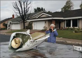  ?? ALLEN J. SCHABEN/LOS ANGELES TIMES ?? A woman takes a photo Monday of airplane parts that landed on her street as workers remove airplane wreckage after a crash of a Cessna airplane in a Yorba Linda neighborho­od on Sunday.