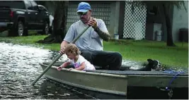  ??  ?? Lemay Acosta, con su hija Layla y su perro, en el barrio inundado de Plantation