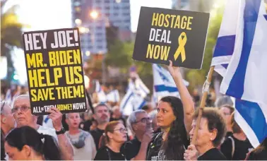  ?? PHOTO: JACK GUEZ/AFP ?? Relatives and supporters hold placards and wave national flags during a demonstrat­ion calling for their release, in Tel Aviv on Saturday.